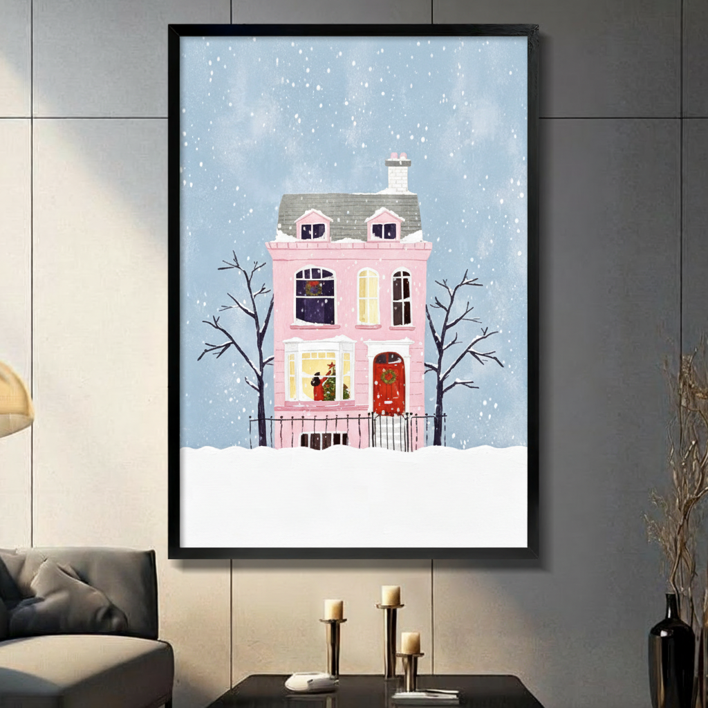 Whimsical flat illustration of a pink Victorian house with a red door and wreath surrounded by bare trees in falling snow Christmas wall art framed print in living room with light gray panel wall and dark sofa