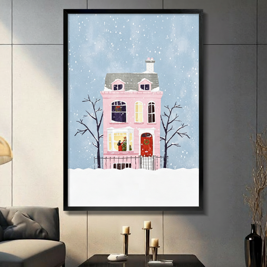 Whimsical flat illustration of a pink Victorian house with a red door and wreath surrounded by bare trees in falling snow Christmas wall art framed print in living room with light gray panel wall and dark sofa