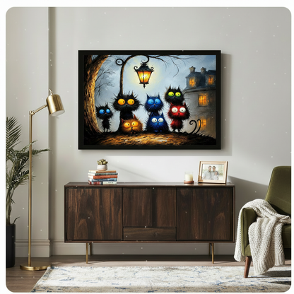 Framed canvas of quirky black, blue and red cats with cartoon-style eyes gathered under a vintage lantern beside a haunted house, styled above a wooden sideboard in a living room