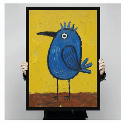 Close-up of a black framed art print showing a bold round blue bird with a spiky crown, single white eye, and thin black legs on a vivid yellow and brown textured background, held up by two hands