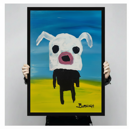 Close-up of a black framed art print showing a quirky white dog with large black eyes, pink open mouth, and black legs on a vivid blue and yellow background, signed Burnich, held by two hands