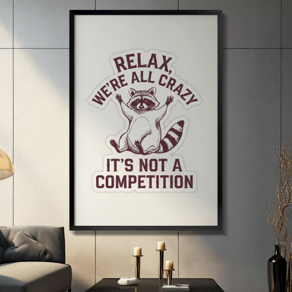 Framed wall art print featuring a funny raccoon illustration with the text Relax We're All Crazy It's Not A Competition, displayed in a modern living room above a console table