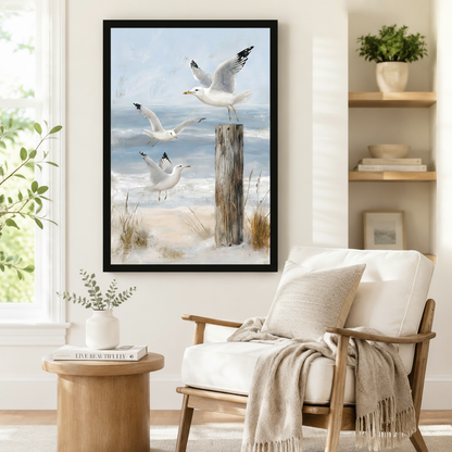 Framed coastal wall art of three seagulls in dynamic flight above beach dunes and a weathered post, styled beside a linen armchair in a serene Scandinavian reading nook