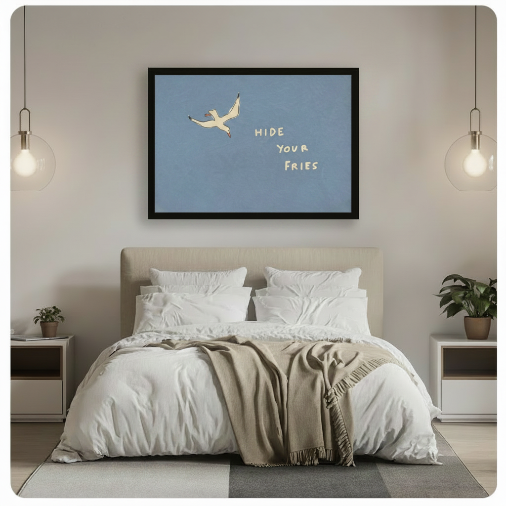 Black framed funny seagull Hide Your Fries coastal quote canvas wall art hung above a beige upholstered bed with white linen bedding in a minimalist bedroom with glass globe pendant lights and potted plants