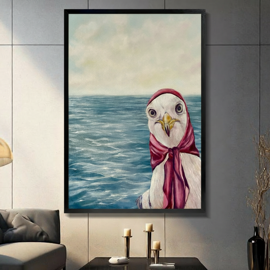 Framed canvas wall art of an oil-painted seagull wearing a red headscarf against a blue ocean background, displayed above a console table with candlesticks in a modern grey living room