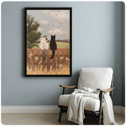 Framed Siamese and black cat countryside fence wall art beside wooden accent chair with linen throw - whimsical pastoral cat canvas print for reading nook or study