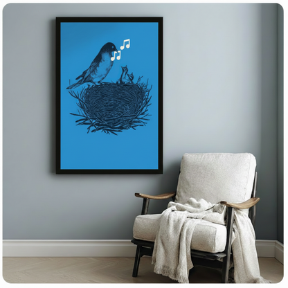 Black framed vintage bird art print showing songbird with floating music notes and baby chicks in twig nest on vivid blue background, styled beside white linen armchair on grey wall