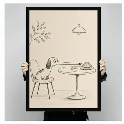Person holding a black framed funny pencil sketch long-nosed dachshund reaching for croissant and coffee on cafe table art print on cream background against a light gray backdrop