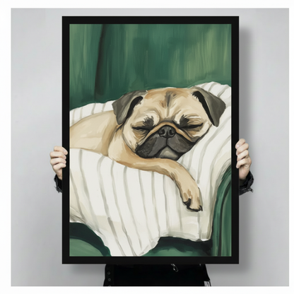 Close-up of black framed sleeping pug wall art print held by hands, showing detailed oil painting style illustration of pug on green velvet sofa