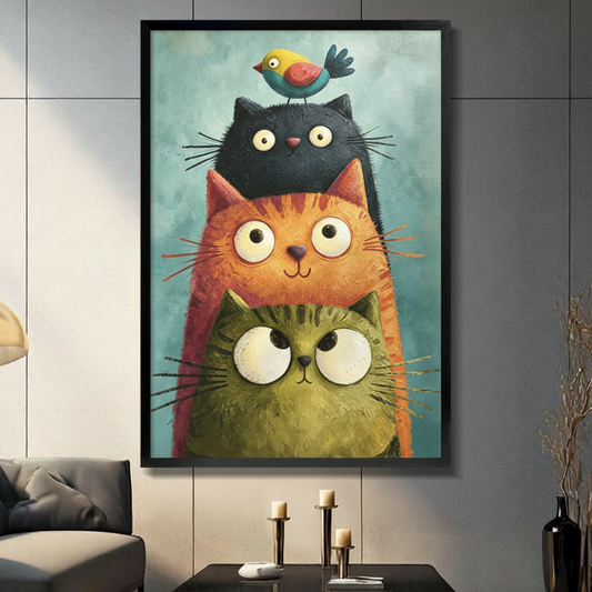 Whimsical impasto oil painting of three chubby stacked cats a mossy green cat an orange tabby and a black cat topped with a tiny colorful bird all with large round expressive eyes on a teal brushstroke background funny cat wall art framed print in a living room with dark gray panel wall dark sofa and black vase