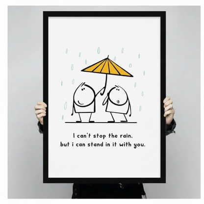 Person holding a large black framed minimalist friendship quote canvas art print showing print size scale with two round cartoon friends sharing a yellow umbrella in teal rain and the text I can't stop the rain but I can stand in it with you