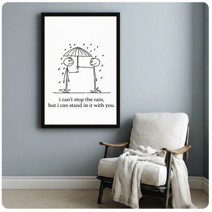 Black framed minimalist stick figure couple under umbrella in rain canvas print beside linen armchair on blue-grey wall - sweet romantic love quote wall art in black and white hand-drawn style for reading nook or bedroom decor