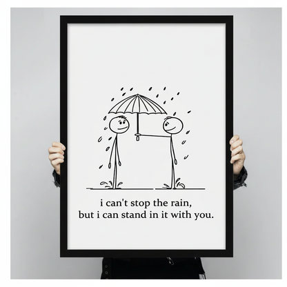 Person holding large framed stick figure couple sharing umbrella in rain canvas print with both hands - close up view of minimalist black and white romantic love quote wall art with clean hand-drawn illustration and black frame finish