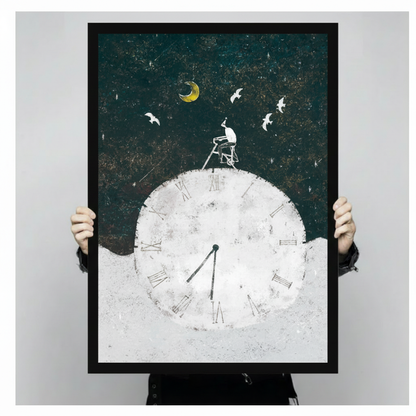 Person holding a large black framed surrealist illustration canvas art print showing print size scale with a small figure on a ladder atop a giant white Roman numeral clock under a golden crescent moon with white birds on a deep teal night sky
