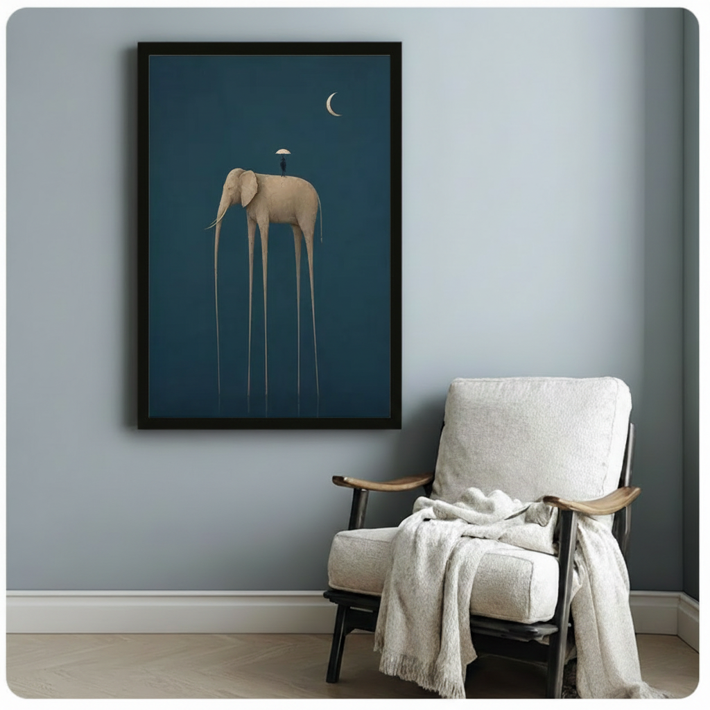Black framed dark teal minimalist surrealist elephant wall art with elongated legs, tiny umbrella figure, and gold crescent moon, styled beside a white linen armchair with a draped throw on a soft blue-grey wall