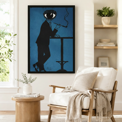 Surrealist eye-head man in black suit smoking pipe black framed art print in deep blue beside a white linen armchair with open wood shelving in a Scandinavian living room