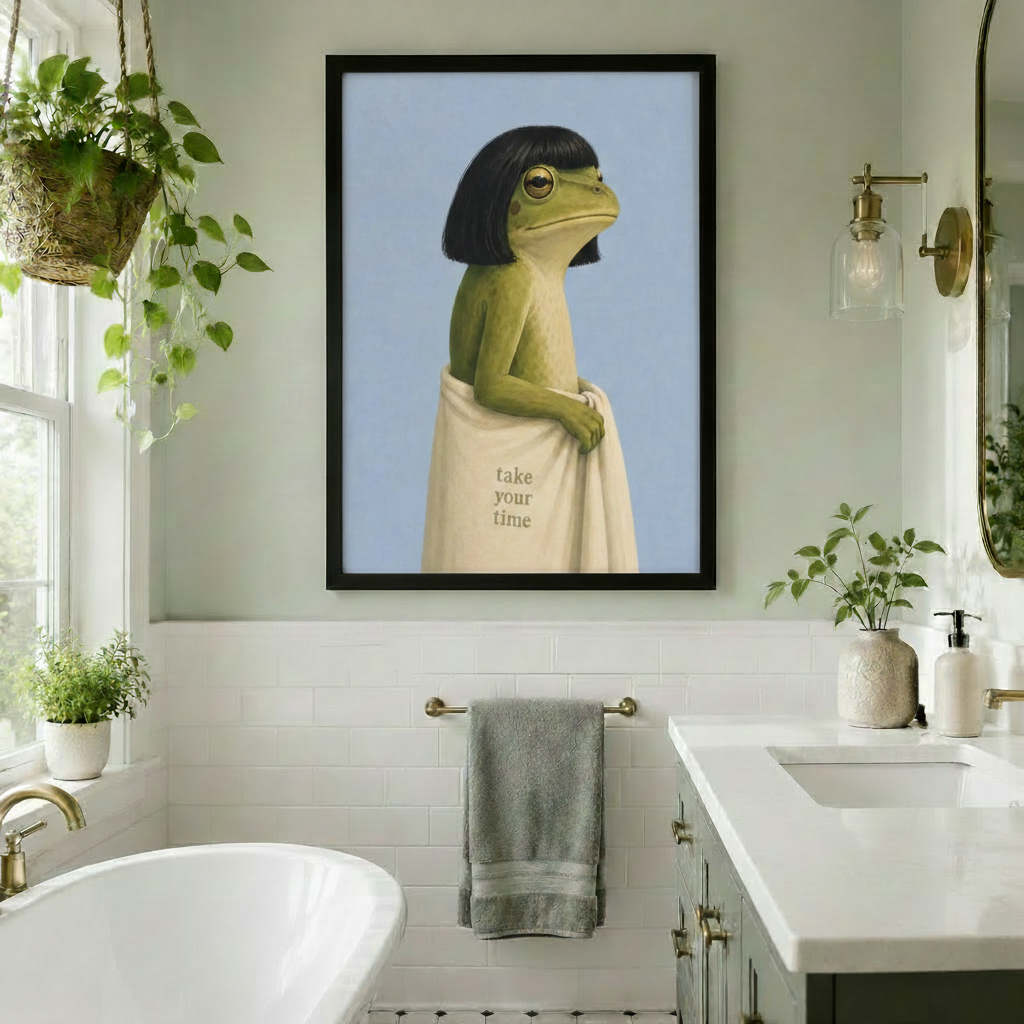 Black framed surreal frog with black bob haircut and cream take your time towel canvas art displayed in a bright white subway tile bathroom with a freestanding bathtub, brass towel bar, hanging pothos plant, and gold sconce lighting