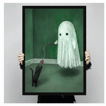 Person holding large framed surreal whimsical oil painting round draped white ghost with two dark hollow eyes hovering in a moody dark green corner room dangling a cat feather wand downward as a curious black cat rears up on hind legs pawing at the hanging tassel casting a soft shadow on the green floor canvas print with both hands against light grey background - close up size reference of funny ghost playing black cat green wall art with black frame finish