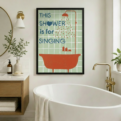 Framed retro bathroom wall art print reading "This Shower is for Singing" with a bold orange bathtub illustration on mint green tiles, hung on a white wall beside a freestanding soaking tub with gold fixtures