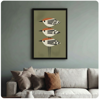 Framed mid-century modern bird art print hung above a cream sofa in a blue-grey living room, featuring three stacked geometric birds