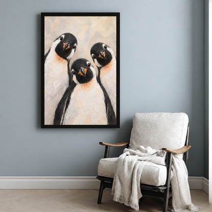 Textured oil painting style illustration of three chubby penguins with black heads orange beaks and peach-tinted white bellies huddling close together and looking forward on a warm cream background cute penguin wall art framed print beside armchair blue-gray wall