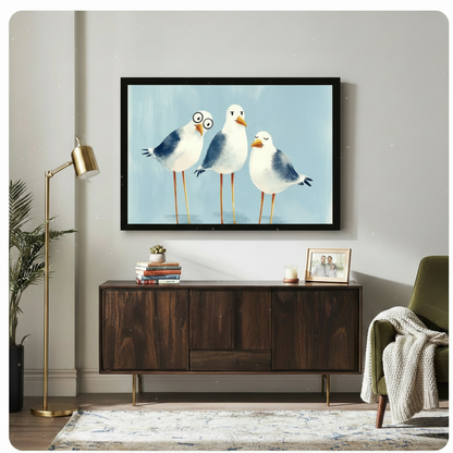 Three chubby seagulls with funny expressions one wearing round glasses on a soft blue background funny coastal seagull wall art framed print above a dark wood sideboard with gold floor lamp and green armchair