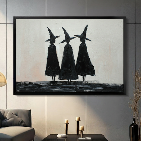 Framed black and white oil painting wall art of three witch silhouettes in pointed hats and dark cloaks standing together, displayed on a grey panelled wall in a moody modern living room