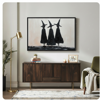 Black-framed three witches silhouette art print hung above a mid-century walnut sideboard in a light neutral living room, bold minimalist gothic wall decor with cream and black palette