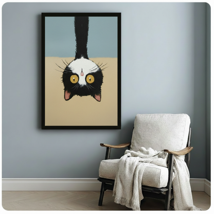  Playful black and white cat upside-down wall art with striking yellow eyes, black framed print styled above white linen armchair with draped blanket in cozy reading nook