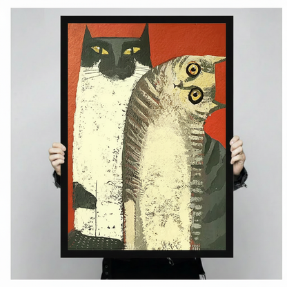 Person holding a black-framed retro pop art canvas print of two cats on red background, showing print size and frame detail