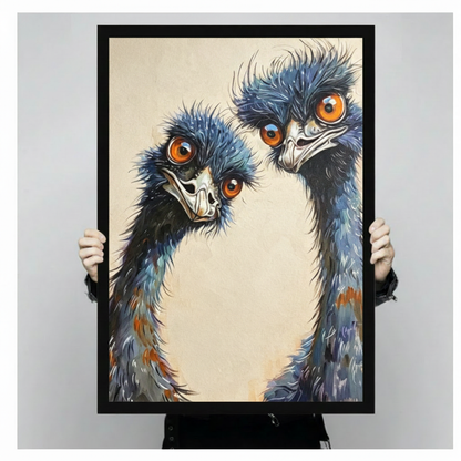 Pair of wide-eyed emus with shaggy blue feathers and vivid orange eyes on a warm cream background funny emu wall art framed print held against a light gray background