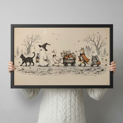 Hands holding a large black framed horizontal canvas print of a charming Halloween procession with witch ghost, goose cart, cloaked fox and striped ghost with jack-o-lantern, vintage storybook illustration on warm cream background against a light gray backdrop