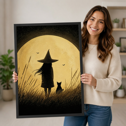 Person holding a large vertical black framed vintage little witch and black cat under a full moon canvas art print showing a witch in a pointed hat and a black cat standing in tall grass gazing at a huge golden moon with bats in a textured sepia sky in a bright plant-filled room