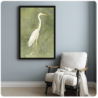 White heron watercolor on an olive background in framed canvas beside a light armchair.