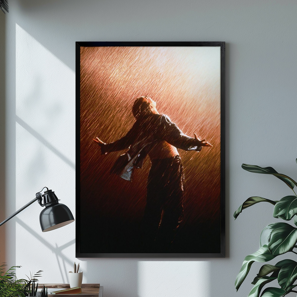 Figure with open arms in warm backlit rain displayed in black framed canvas beside a lamp.