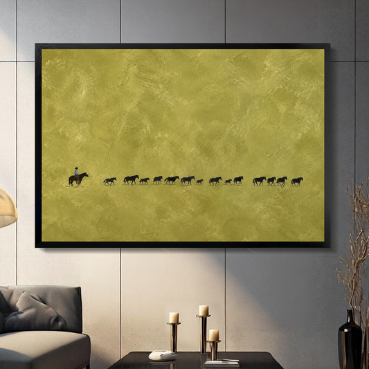 Black framed cowboy and cattle trail canvas artwork displayed on a gray wall in a neutral room.
