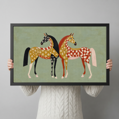 A person holds framed folk horses artwork to demonstrate its landscape proportions and scale.