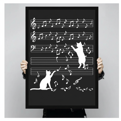 Person holding a black framed portrait canvas featuring cats and musical notes.