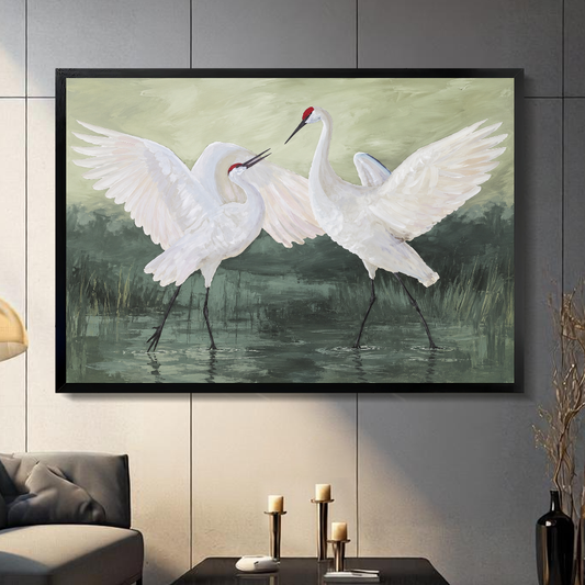 Black framed canvas depicting two white cranes with open wings on a gray paneled wall with candles.