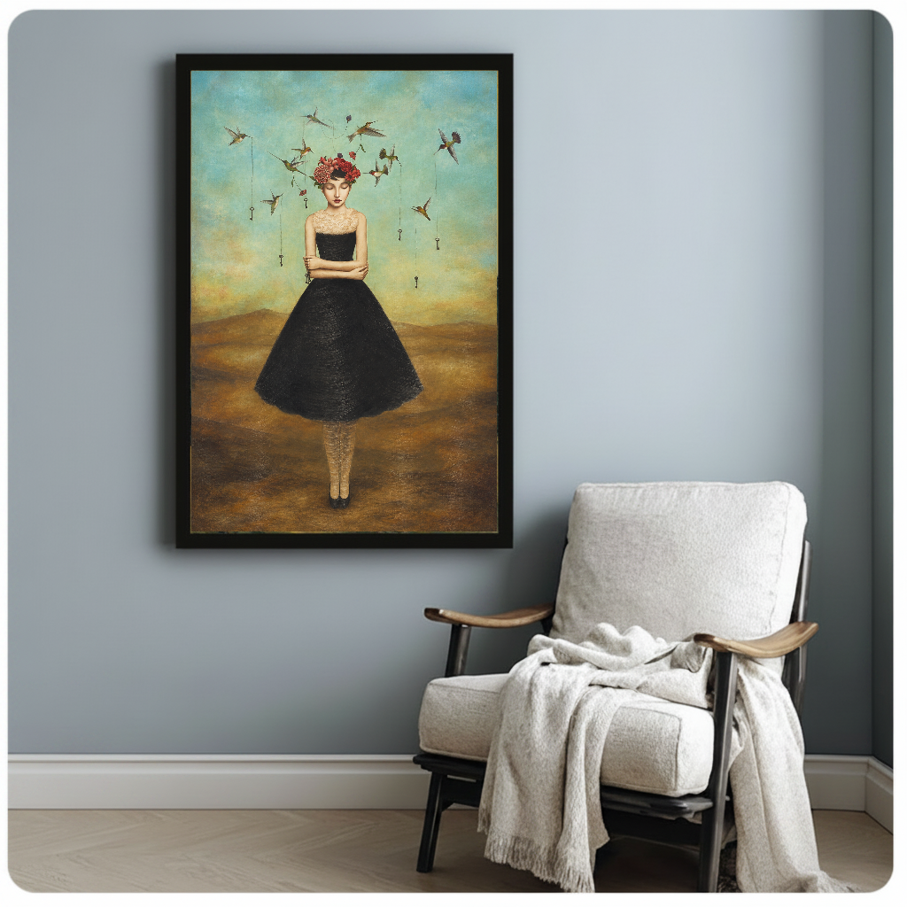 Framed artwork of a flower crowned woman with hummingbirds beside a pale reading chair against a gray wall.