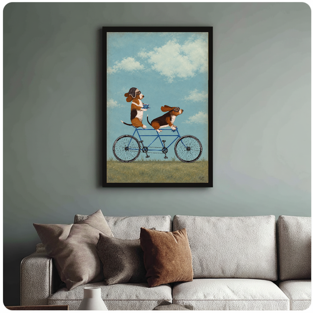 Framed tandem bicycle beagles painting above a sofa with muted cushions against a green-gray wall.