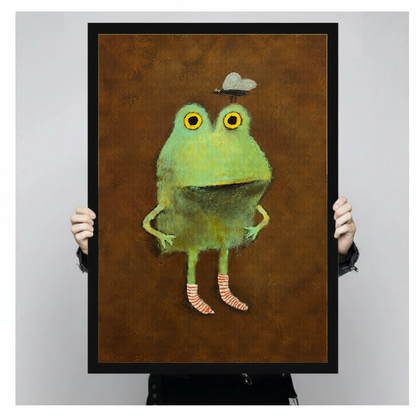 Framed artwork of a green frog wearing striped socks held by a person against a pale backdrop.