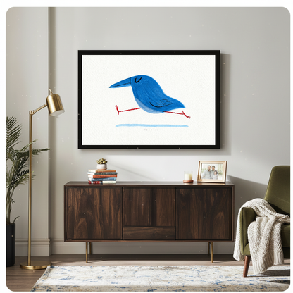 Framed running blue bird artwork above a wooden cabinet beside a gold lamp.