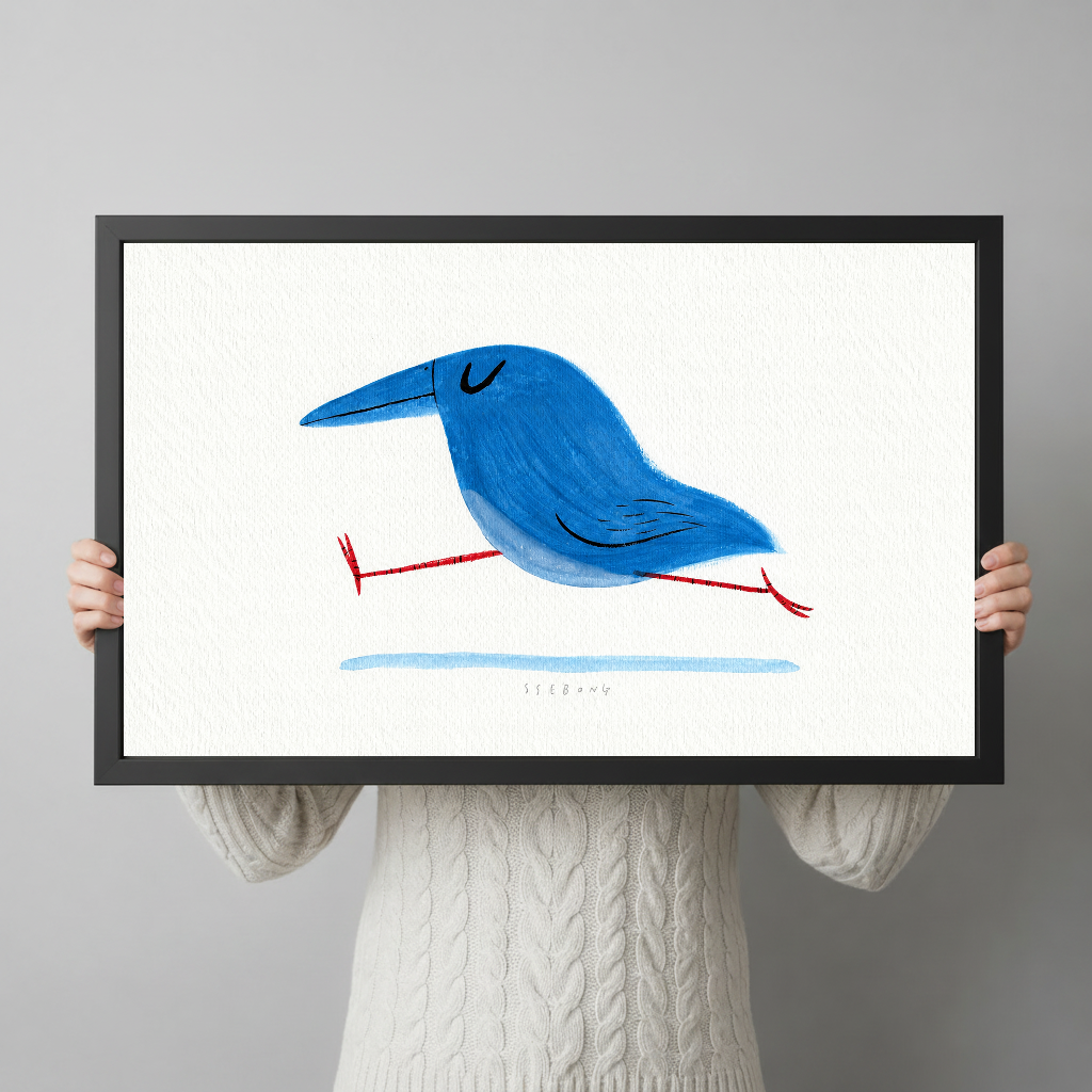 Person holding black framed running blue bird artwork against a plain pale background.