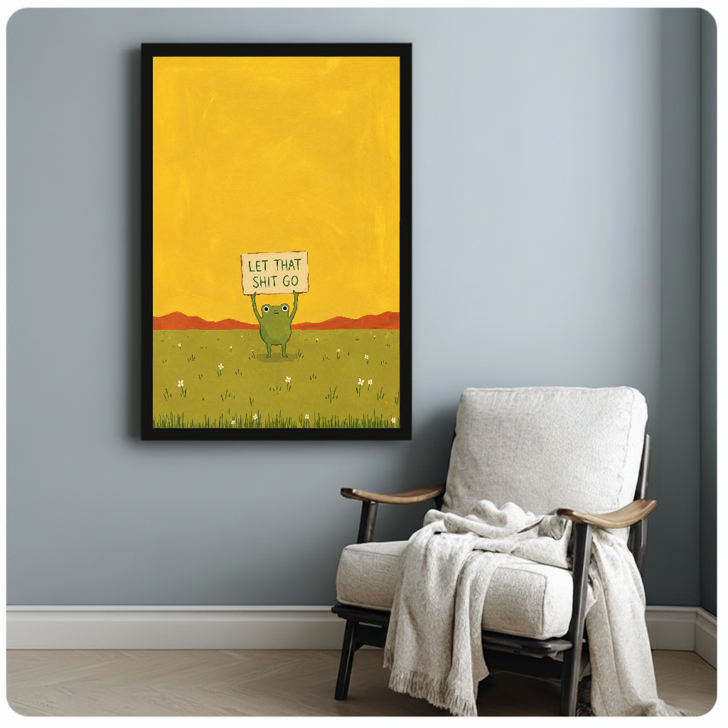 Framed artwork of a green frog holding a humorous sign beside a pale reading chair against a gray wall.