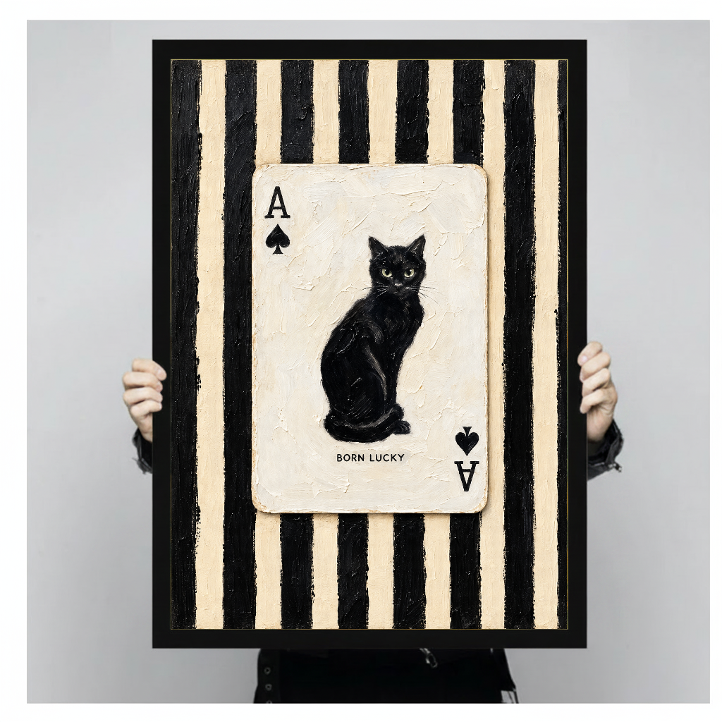 Framed artwork of a black cat inside an ace playing card held by a person against a pale backdrop.