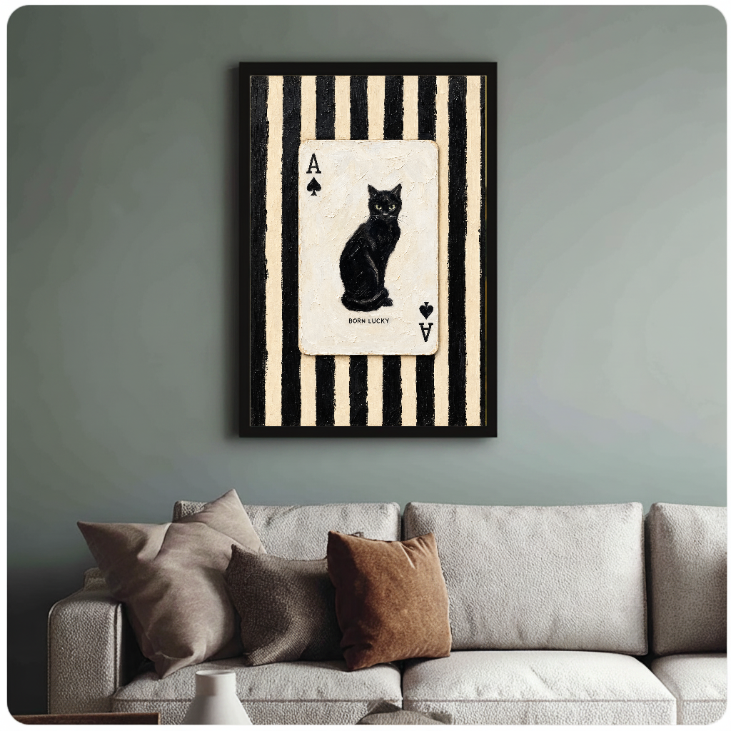 Framed artwork of a black cat inside an ace playing card above a sofa with muted cushions.