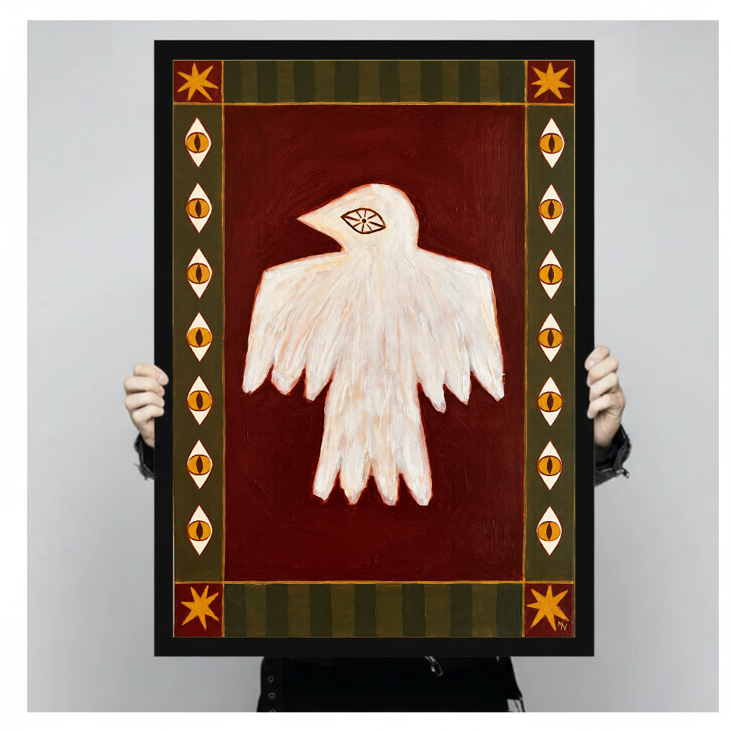 Person holding black framed folk bird with eyes artwork against a plain pale background.