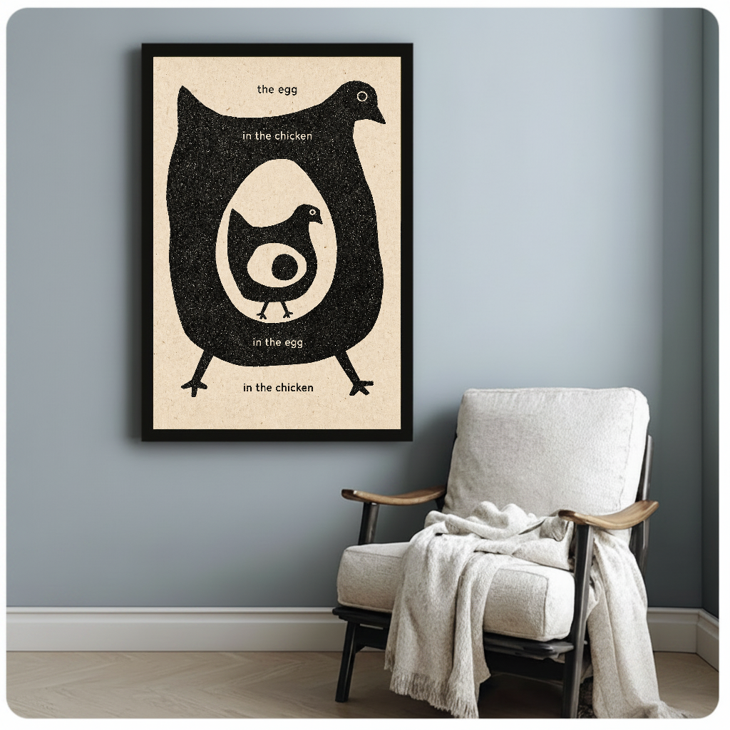 Framed artwork of a chicken and egg question beside a pale reading chair against a gray wall.