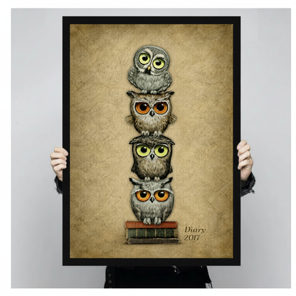 Person holding black framed stacked bookish owls artwork against a plain pale background.